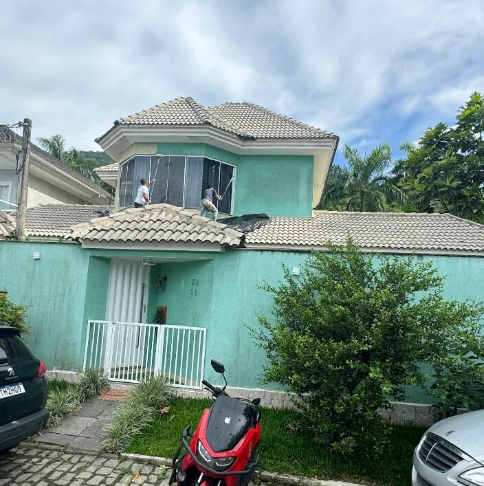 Equipe pintando telhado e fachada de casa